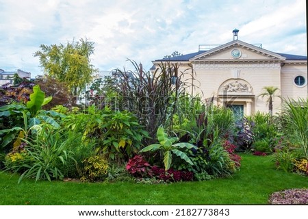 Amazing mixder   or flower bed  of tall perennials in Garden of plants in Paris in fanatstic autumn: yellow and red flowers. Small Part of some building in background Royalty-Free Stock Photo #2182773843