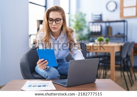 Young blonde woman business worker using laptop and touchpad at office