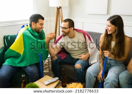 Smiling young men and sports fans celebrating their sports team victory while hanging out with friends