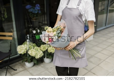 Close up of hands of florist woman in the floral came outside of the shop she take with her flowers bouquet and take care after the flowers before giving it to the buyer.