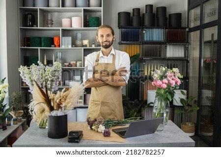 Man florist at his own floral shop taking care of flowers. People, business, sale and floristry concept. Happy smiling florist male making flower bunchs at flower shop. Royalty-Free Stock Photo #2182782257