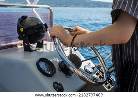 Driving motorboat on holiday. Man sailing an inflatable rubber motor boat on the sea. Boat rental close up Royalty-Free Stock Photo #2182797489
