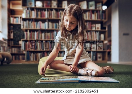 Child solving riddle in book in school library. Primary school pupil is involved in book with riddles. Smart girl learning to solve problems. Benefits of everyday practice. Child curiosity Royalty-Free Stock Photo #2182802451