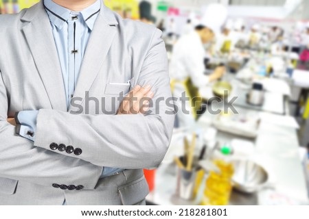 Business Man standing against the Background of Kitchen as Concept of Restaurant , Catering or Food service.