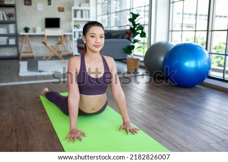 young asian woman working out and doing yoga in the cobra pose at home, healthy concept.