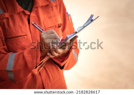 Action of safety officer is wirtinng and check on checklist document during safety audit and inspection at drilling site operation. Industrial expertise occupation photo. Royalty-Free Stock Photo #2182828617