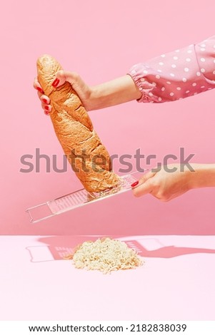 Food pop art photography. Female hands grating bread, baguette to make breadcrumb for meat isolated over pink background. Vintage, retro style. Complementary colors, Copy space for ad, text