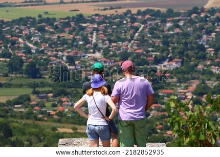 A family looking down from the castle of Madara and taking pictures of the Shumen plain. A family high up on the mountain. Three people. People on top of the mountain