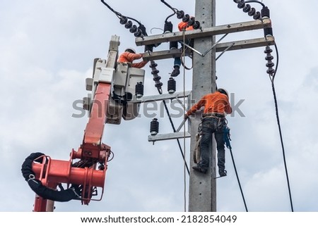 Electricians are climbing on electric poles to install and repair power lines. Royalty-Free Stock Photo #2182854049