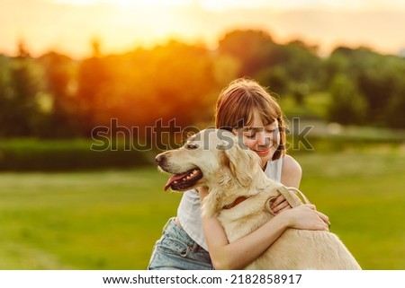 A Portrait of teenage girl petting golden retriever outside in sunset Royalty-Free Stock Photo #2182858917