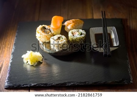 several rolls of sushi on a stone plate in a dark styling