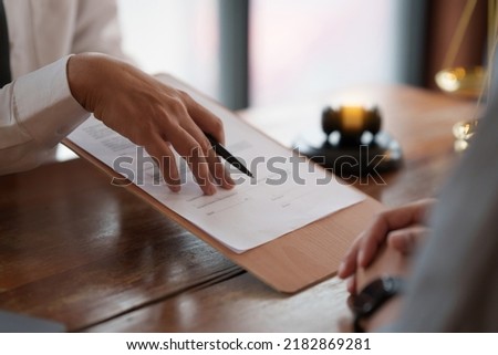 Business person and lawyers discussing contract papers with brass scale on wooden desk in office. Law, legal services, advice, Justice concept.