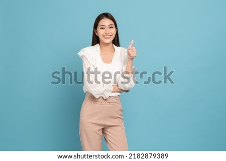 Young beautiful asian woman with smart casual cloth smiling and giving thumbs up isolated on blue background