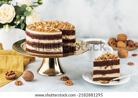 Freshly prepared delicious chocolate cake with walnuts on a white table on a cake stand Royalty-Free Stock Photo #2182881295