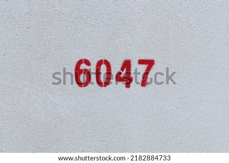Red Number 6047 on the white wall. Spray paint.
