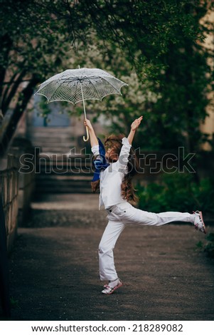 small and pretty girl dancing with lace umbrella in white suit