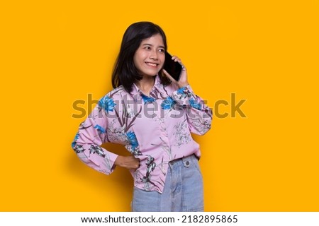 happy young asian beautiful woman using mobile phone isolated on yellow background
