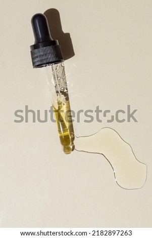 Dropper glass bottle branding mockup. Cosmetic pipette. Trendy beige background. Concept of organic and beauty cosmetics. Harsh sunlight. Top view. Royalty-Free Stock Photo #2182897263