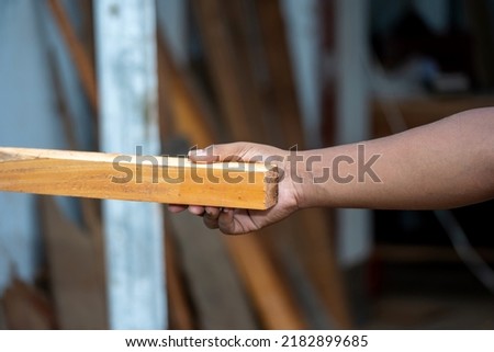 He is holding a piece of the wood plank.