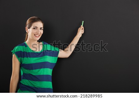 Happy woman writing on  chalkboard, with copy space for designer