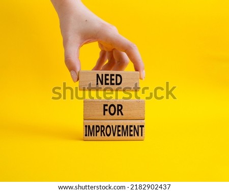 Need for Improvement symbol. Wooden blocks with words Need for Improvement. Beautiful yellow background. Businessman hand. Business and Need for Improvement concept. Copy space.