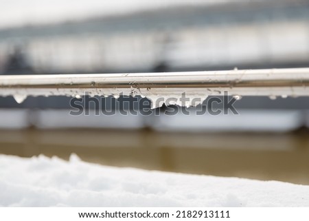 handrail, railing with water drops and wet snow build-up. early spring weather conditions, thaw and snow melting Royalty-Free Stock Photo #2182913111