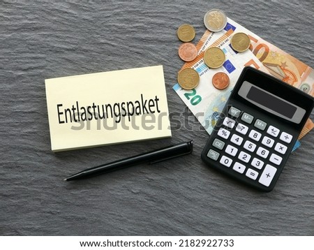 The German word Entlastungspaket  on a notepad with banknotes and a calculator.
 Entlastungspaket means relief package. Royalty-Free Stock Photo #2182922733