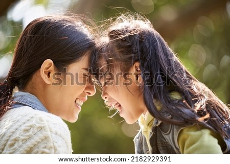 asian mother and daughter having a good time outdoors in city park Royalty-Free Stock Photo #2182929391