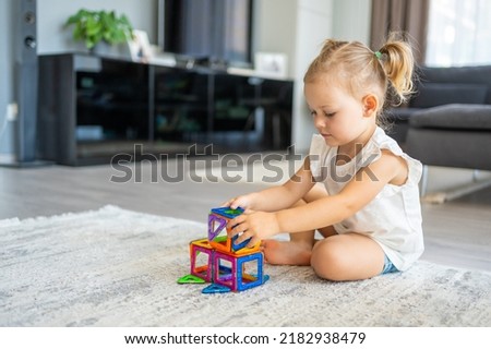 Little girl playing colorful magnet plastic blocks kit at home. The child playing educational games. Early childhood development. High quality photo