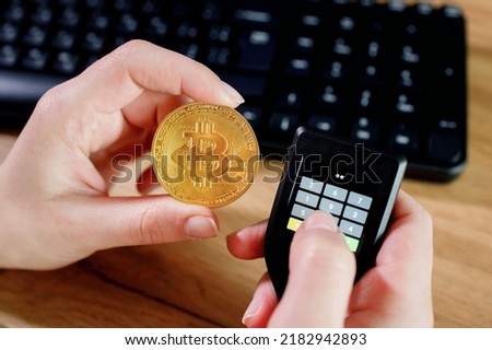 Close up womans hand holding bitcoin and cryptocurrencey hardware cold wallet on keybord background. Secure cryptocurrency storage. Royalty-Free Stock Photo #2182942893