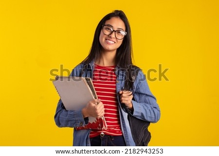 Young student holding backpack and books in studio photo