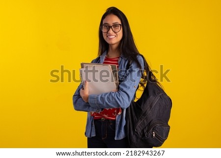 Young student holding backpack and books in studio photo