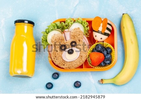 Kids lunch box with funny bear sandwich and boiled egg bee, banana, orange juice. Back to school background. Top view Royalty-Free Stock Photo #2182945879