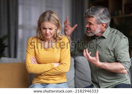 Aggressive Behavior. Portrait Of Abusive Husband Shouting At Wife At Home, Angry Middle Aged Man Screaming At Spouse With Rage, Scared Depressed Woman Suffering Domestic Violence, Closeup Royalty-Free Stock Photo #2182946333