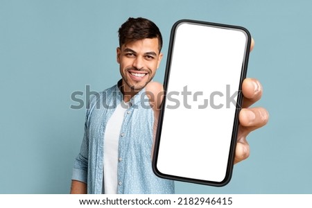 Happy Handsome Middle Eastern Young Man Showing Modern Phone With White Empty Screen And Smiling On Blue Studio Background, Recommending Dating App. Free Space And Mockup For Advertisement, Collage