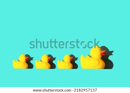 Rubber toy of yellow color Mama-duck and small ducklings on a blue background. The concept of maternal care and love for children, the upbringing and education of children Royalty-Free Stock Photo #2182957137