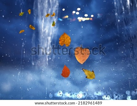 Heavy Rainy Autumn leaves on window rain drops and night city traffic blurred light colorful reflection cold season defocus background 