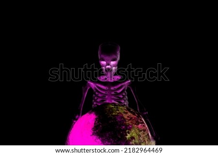 A horrible creepy human skeleton bent over a rotten sphere in a purple glow isolated on a black background.