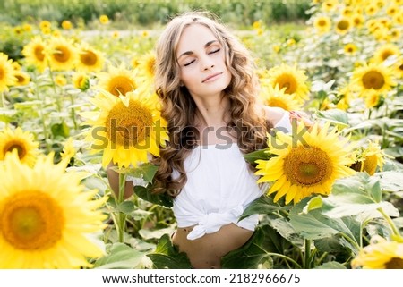 Young blonde girl with long curly hair in a field of sunflowers