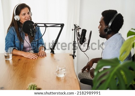 Multiracial hosts streaming podcast together at record studio - Focus on woman microphone