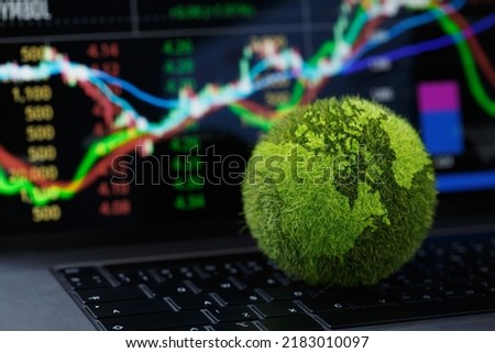 Green Globe on laptop keyboard with Stock graph on the laptop screen. Green business concept. Carbon efficient technology. Digital sustainability. future green energy innovation business trend.