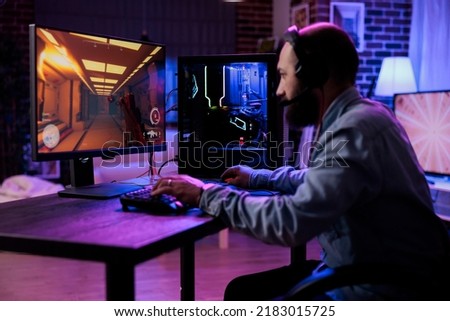 Modern player having fun with video games play competition, using computer to stream online championship. Male gamer playing rpg action tournament game at desk with neon lights. Royalty-Free Stock Photo #2183015725