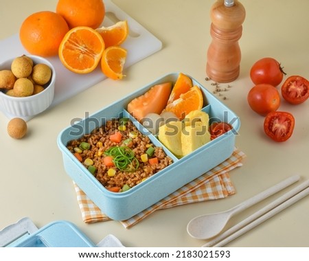 Prepare Children's School Supplies in the lunch box, with ingredients vegetables fried rice, tamagoyaki or omelet, orange, melon, and longan.  Royalty-Free Stock Photo #2183021593