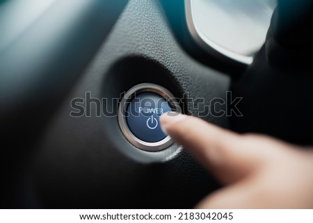 Finger ready to press car engine start stop button - car interior. Driver push the power on off button inside a car.