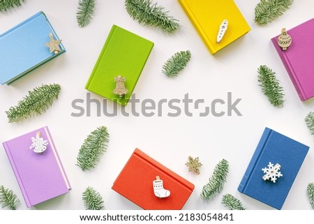 Christmas holiday background with colors paper books, New Year design, green pine branches, wooden toys, colorful covers of books, Christmas flat lay. Reading, studying, education concept, copy space