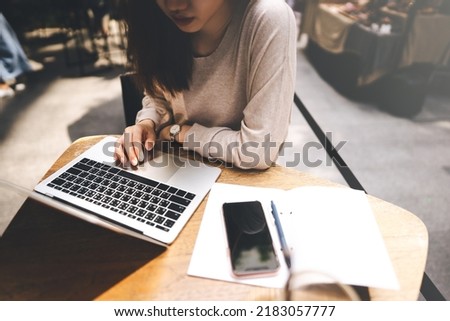 Young adult business freelancer women using laptop for study and work online. Workplace table with computer and mobile phone. People city lifestyle at cafe from home on day concept.