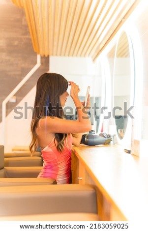 Brunette girl taking a selfie looking in the mirror at the beauty salon, hairdressing