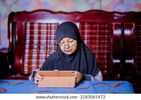 Asian girl playing tablet at home
