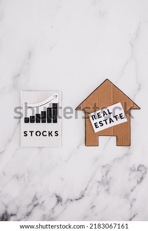 investment opportunities and building wealth conceptual image, house icon next to stock market stats symbol of alternative financial choices