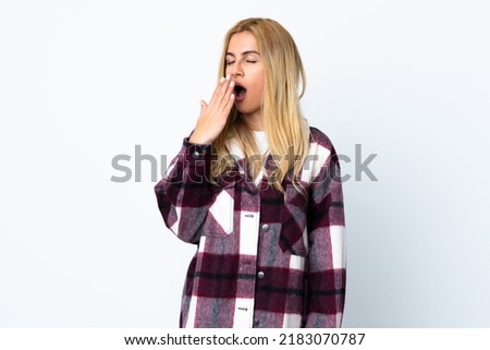 Young Uruguayan blonde woman over isolated white background yawning and covering wide open mouth with hand